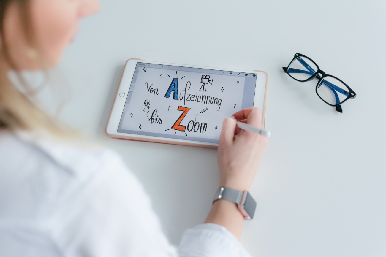 Blick über die Schulter einer Frau, die auf digitales Tablet "A bis Z" schreibt