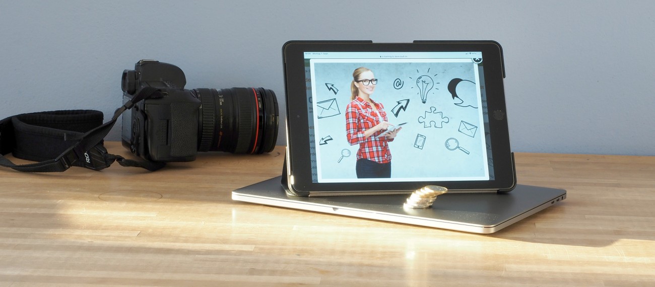 Foto: Tablet auf Tisch mit Kameraobjektiv im Hintergrund