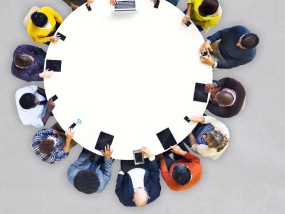 Foto: Mehrere Menschen sitzen um einen runden Tisch