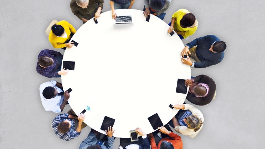 Foto: Mehrere Menschen sitzen um einen runden Tisch